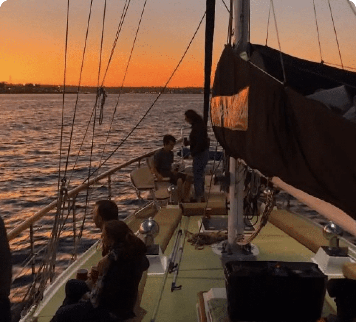 People sailing on a boat at sunset.