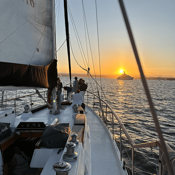Sailing boat cruising at sunset on calm waters.