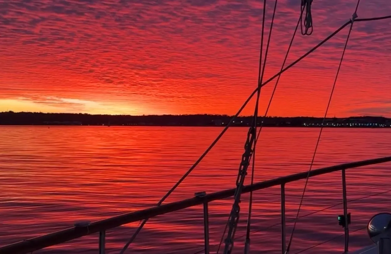 Sailboat railing silhouetted against fiery red sunset