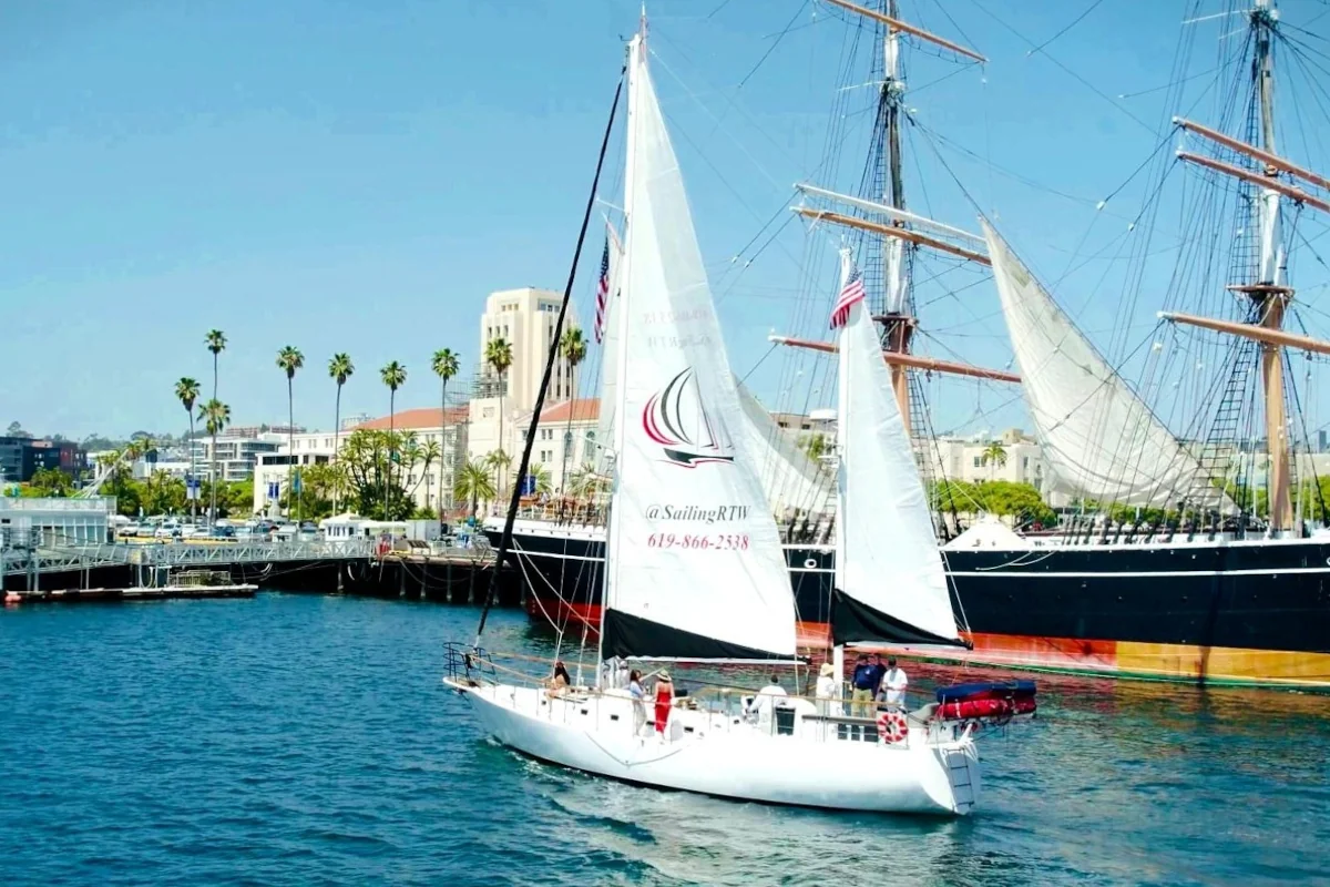 Sloop before historic tall ship and palms