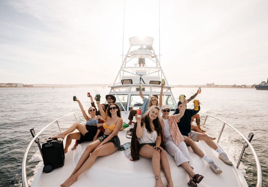 Group of friends enjoying a boat trip, raising drinks and celebrating together.