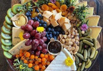 A colorful charcuterie board with fruits, cheeses, nuts, and crackers.