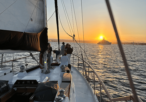 Sailing boat cruising at sunset on calm waters.