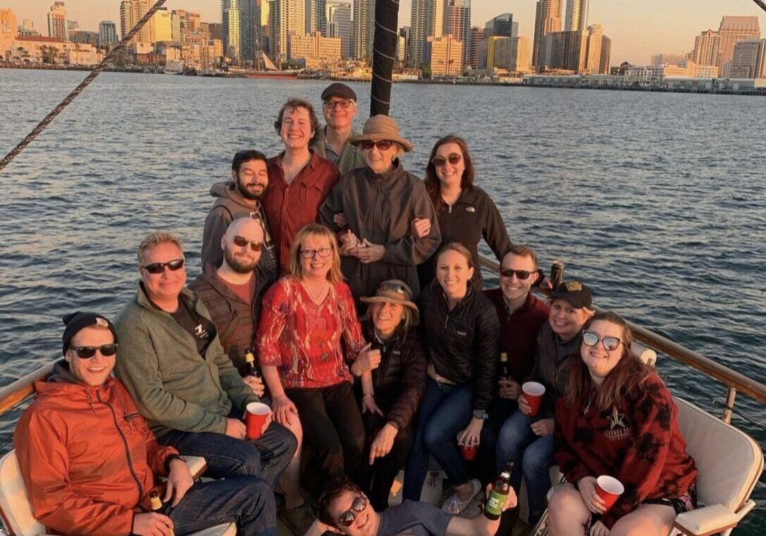 Group enjoying a sunset boat ride with city skyline in the background.