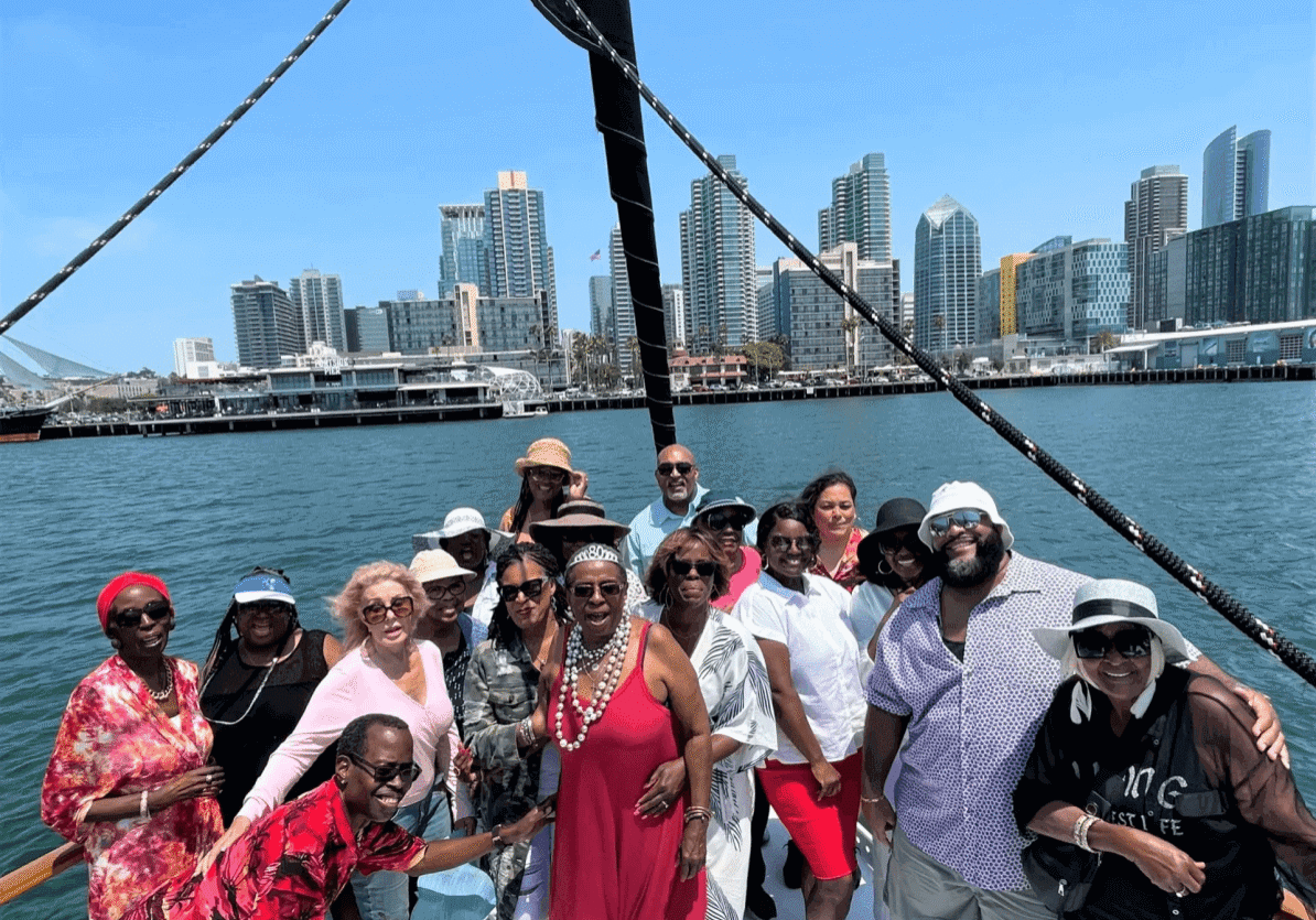 Group posing on boat with city skyline.