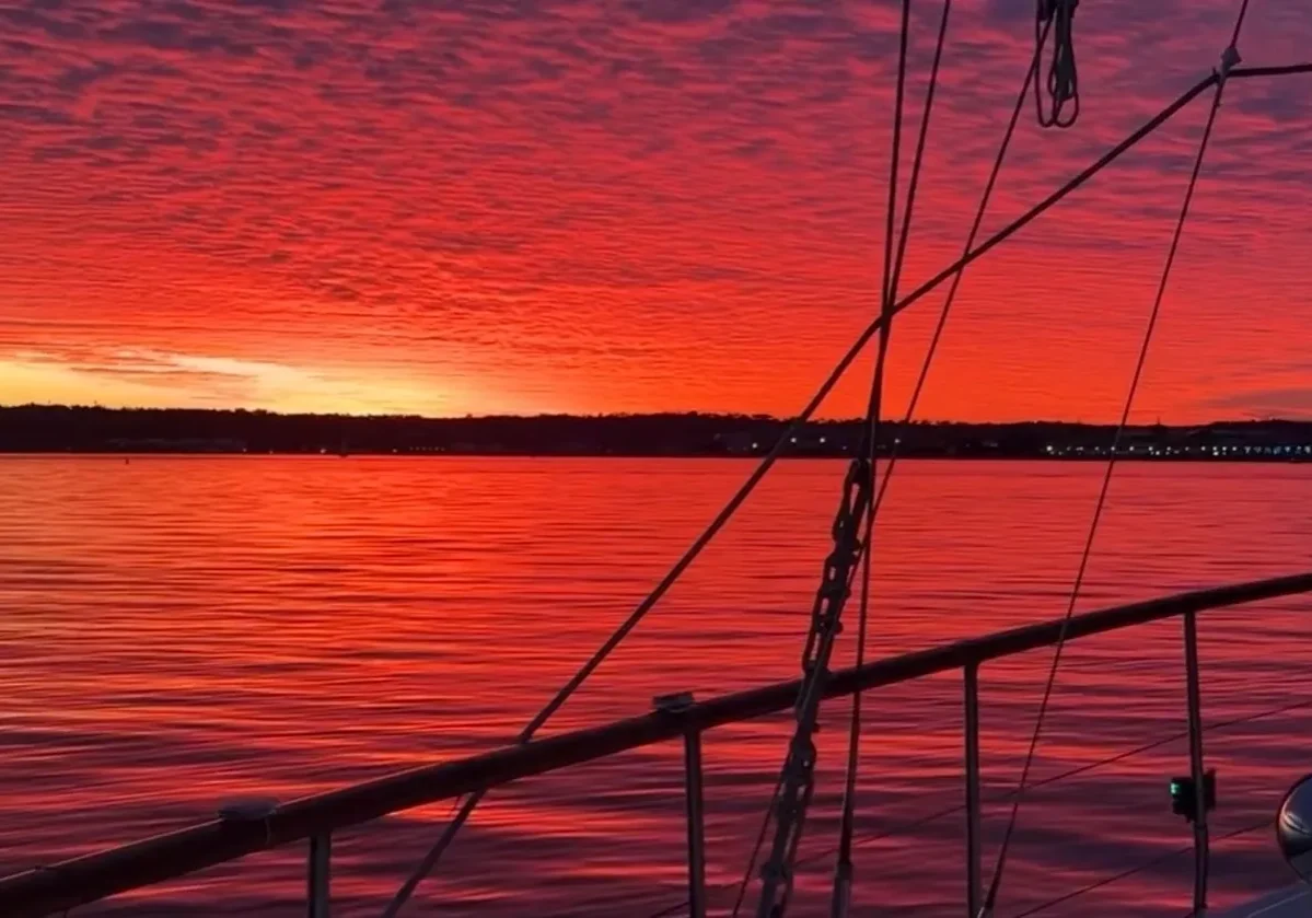 Sailboat railing silhouetted against fiery red sunset