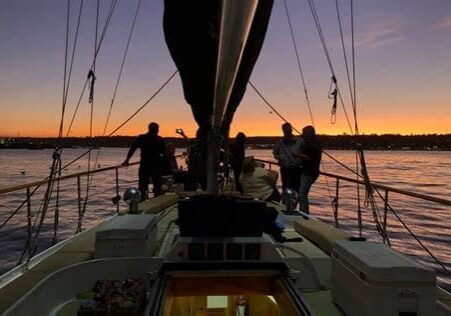 Sailboat at sunset with silhouetted figures.