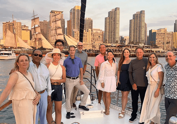 Group of people enjoying a boat party with city skyline at sunset.