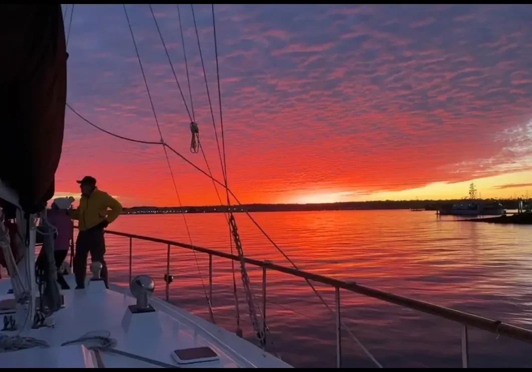 Sailboat at vibrant orange sunset over calm water