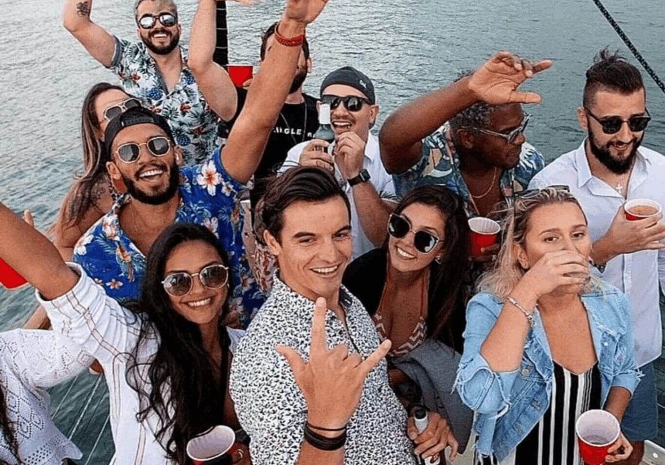 Group of friends enjoying a boat party with drinks and smiles.
