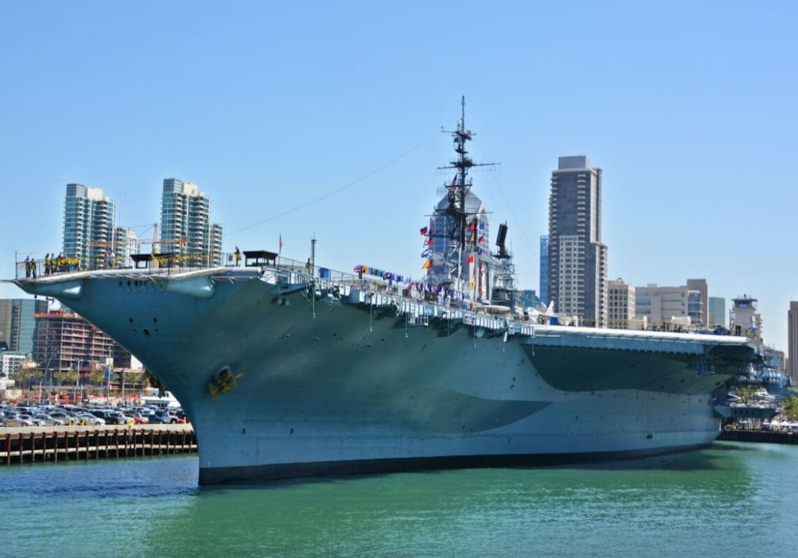 Historic aircraft carrier docked beside urban waterfront